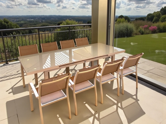 Table repas extensible en aluminium traité époxy blanc avec plateau en verre cappuccino, parfaite pour salons modernes, résistant aux intempéries et facile à entretenir.