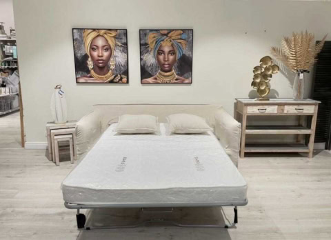 Lit avec double matelas, décorée avec tableaux africains, élégantes plantes dorées, ambiance chaleureuse et sophistiquée, parfait pour un espace déco tendance et unique.