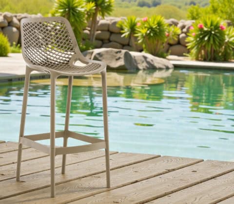 Chaise de bar haute en plastique taupe avec dossier ajouré, idéale pour un espace extérieur ou piscine, allie style moderne et confort pour vos moments de détente en plein air.