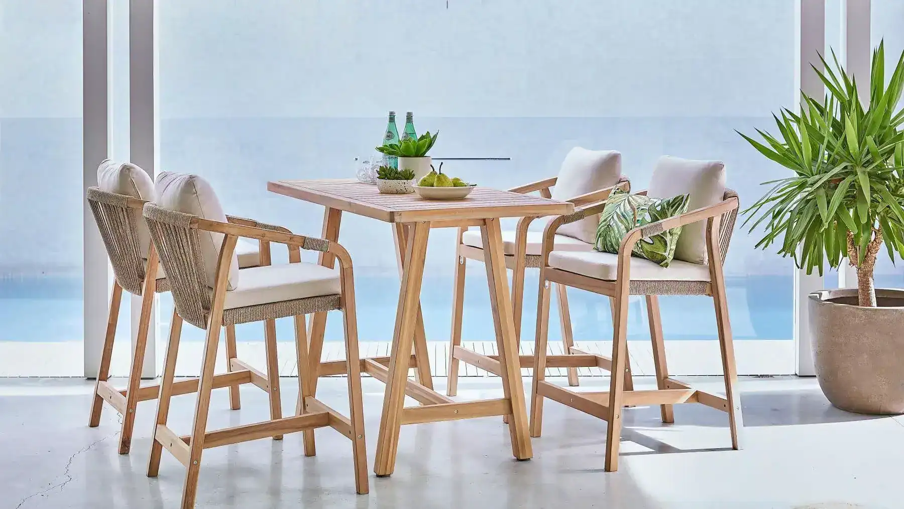 Balcon lumineux avec table et chaises en bois, parfait pour un repas en plein air ou un moment de détente. Design minimaliste et ambiance fraîche pour un espace convivial.